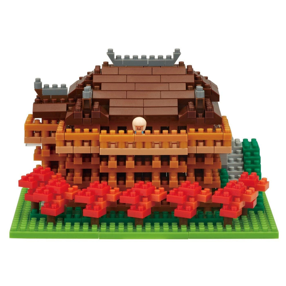 A colorful and intricate model of a castle-like structure made of building blocks, with a small figure of a person standing on the roof.