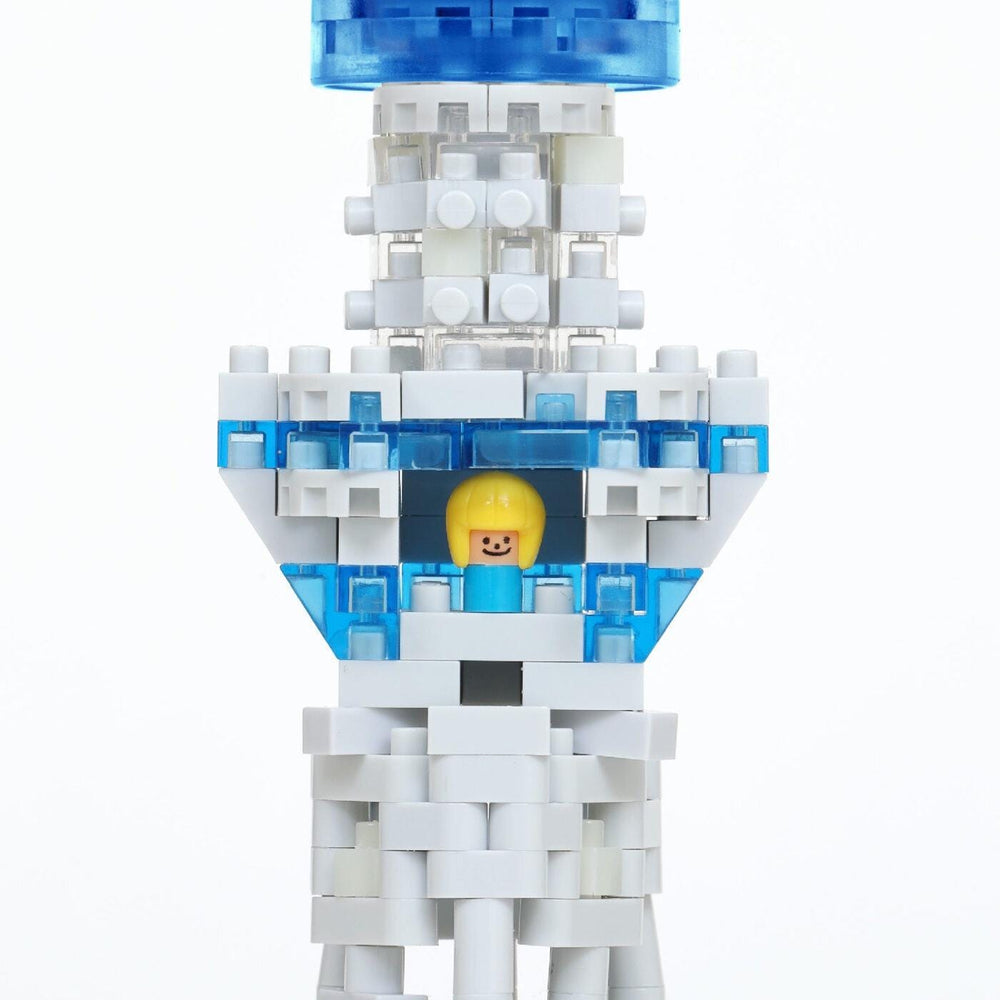 A close-up of a white and blue Lego structure with a yellow figure inside, set against a white background.