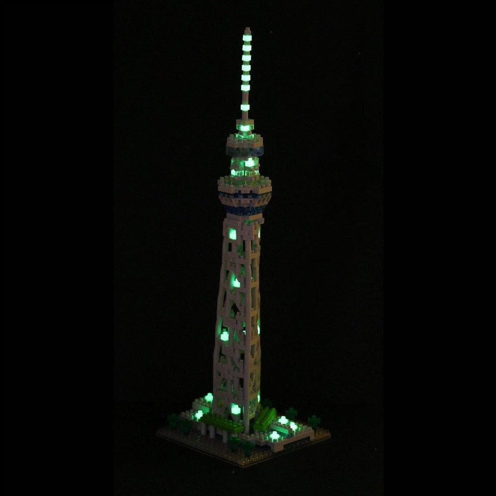 A tall, illuminated tower made of small, glowing blocks stands against a dark background.