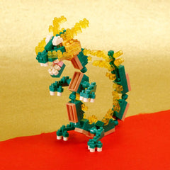 A colorful dragon-shaped toy made of small building blocks in shades of green, yellow, and orange, standing on a red surface.