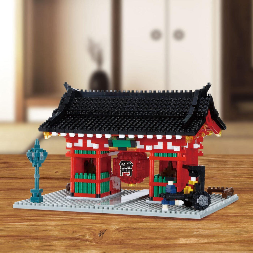 A colorful, intricately designed toy temple made of small building blocks, featuring a red roof, green and white accents, and a red lantern hanging from the center.