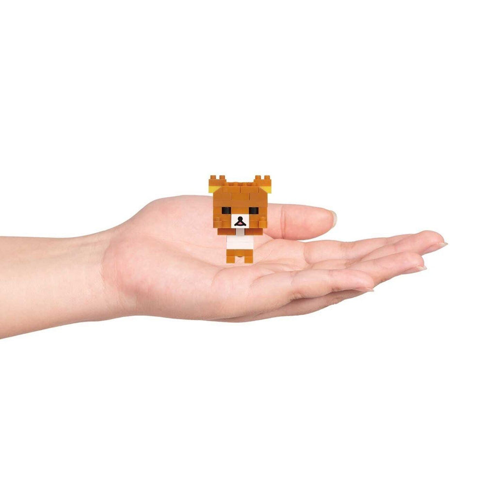 A small, pixelated brown bear figurine is being held in a person's hand against a white background.
