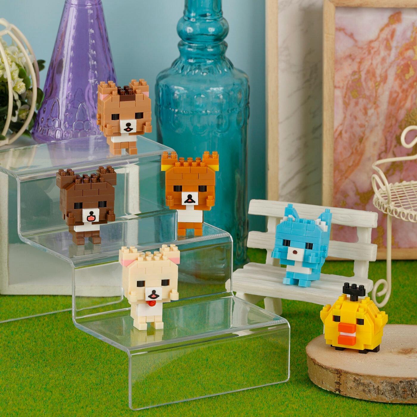 A collection of small, colorful, pixelated animal figurines displayed on a glass shelf, with a blue bottle and other decorative items in the background.