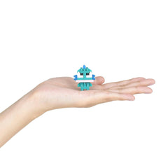 A small, green, pixelated robot figure is being held in a person's hand against a white background.