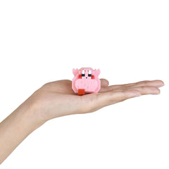 A hand holding a small pink, brick-like object with a face and eyes.