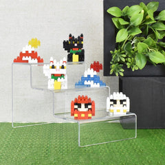 A display of colorful, pixelated character figurines on a clear, three-tiered stand, with a potted plant in the background.