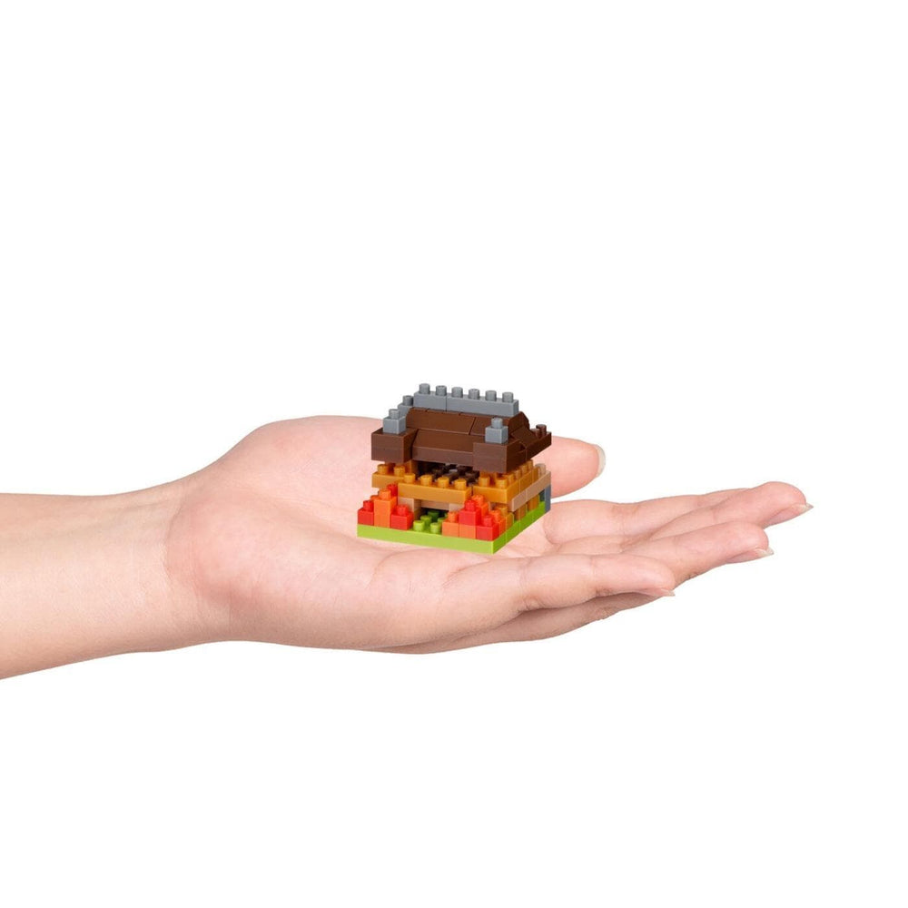 A hand holding a small, colorful building made of building blocks.