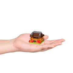 A hand holding a small, colorful building made of building blocks.
