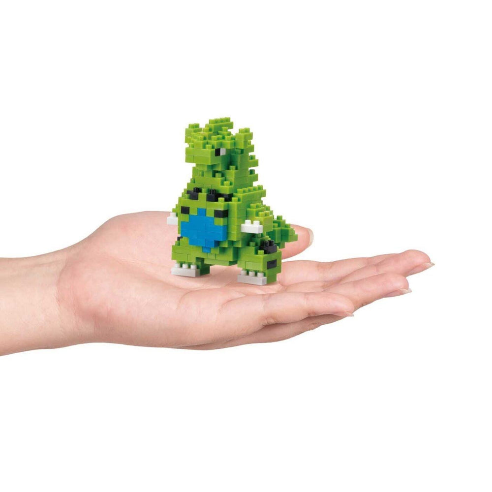 A hand holding a small green and blue pixelated toy.