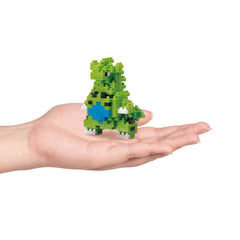 A hand holding a small green and blue pixelated toy.