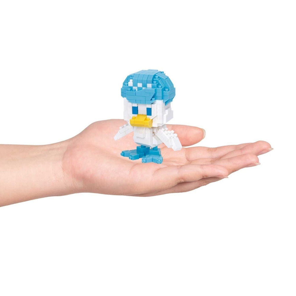 A hand holding a small, colorful, pixelated toy figure of a duck.