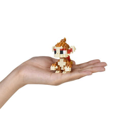 A small, pixelated monkey figurine is being held in a person's hand against a white background.