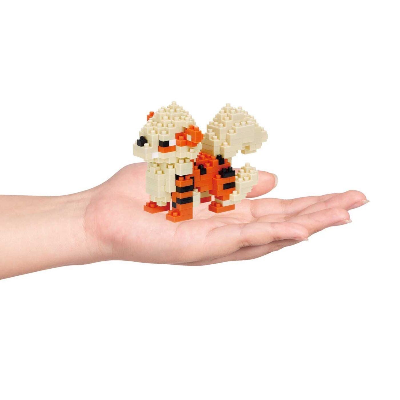 A hand holding a small, colorful, and intricate toy made of small, colorful building blocks.