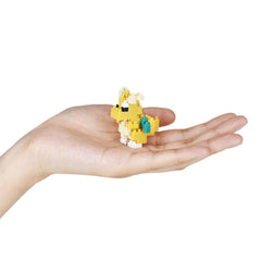 A hand holding a small yellow and white toy, which appears to be a pixelated character or toy.