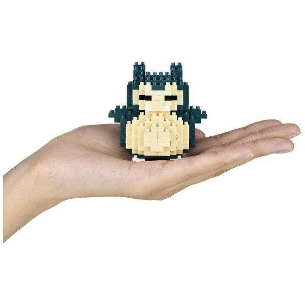 A hand holding a small, pixelated character resembling a Pokémon.