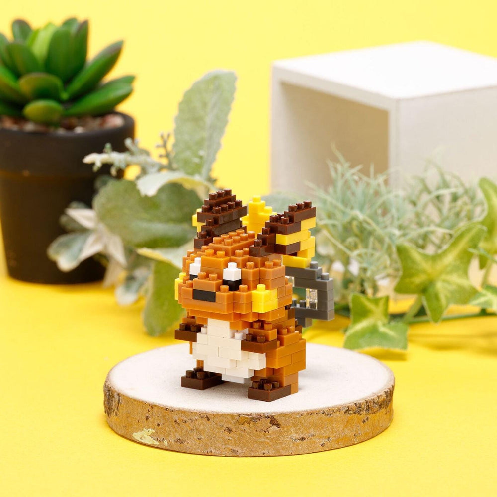 A small, colorful pixel art figurine of Pikachu, a popular Pokémon character, is displayed on a wooden stand against a yellow background.