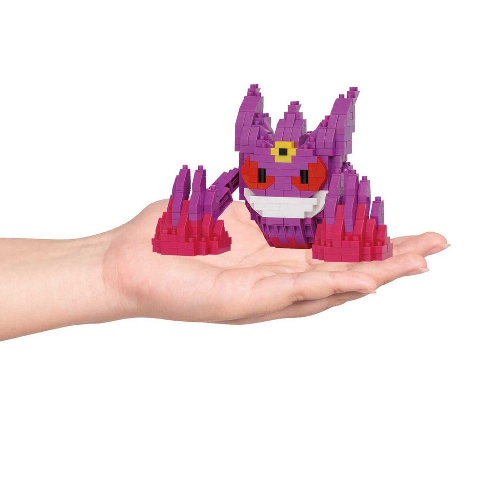 A hand holding a small, colorful, pixelated toy resembling a character from a video game.