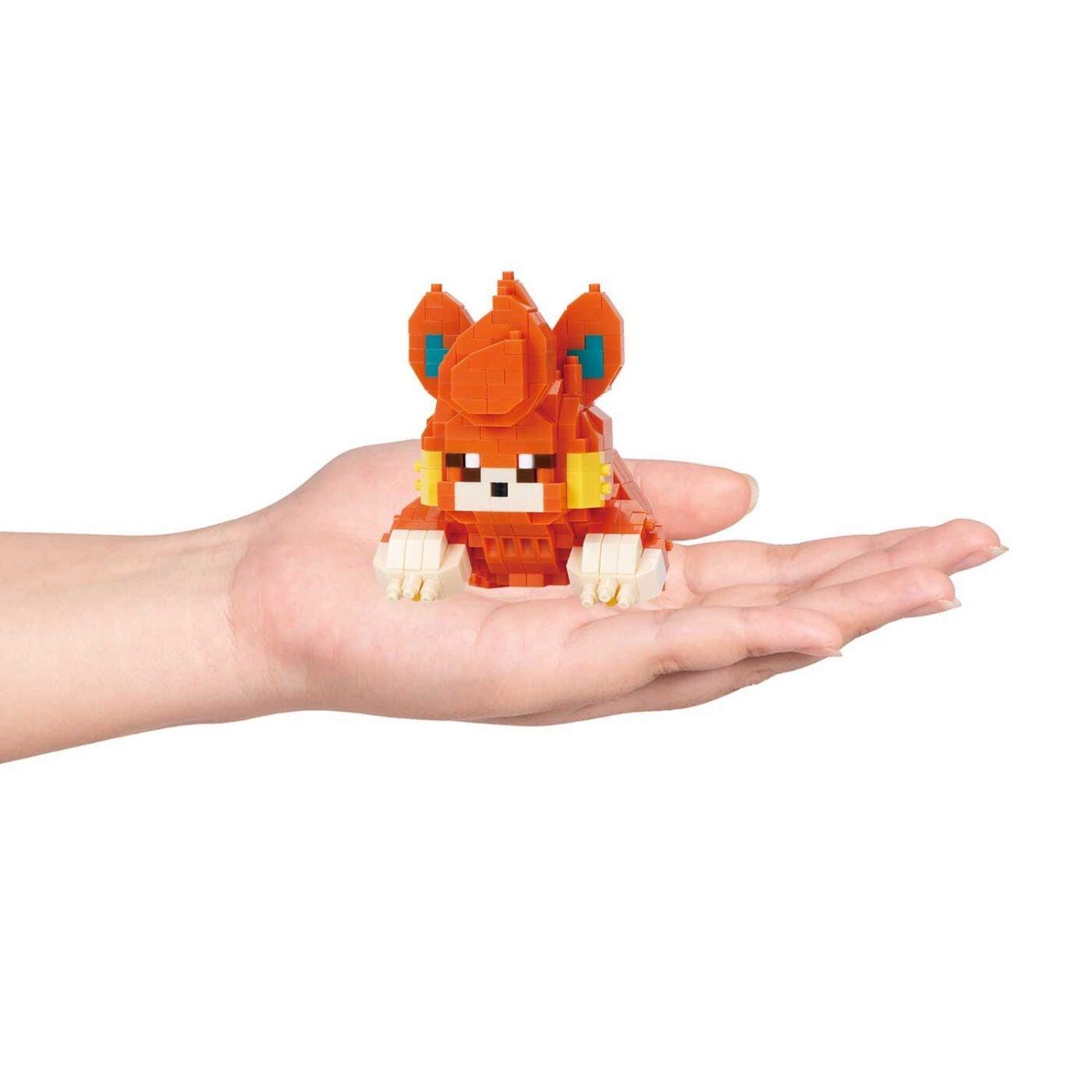 A hand holding a small orange and white toy resembling a cat or a dog.