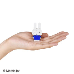 A hand holding a small white and blue toy, which appears to be a small robot or figurine.