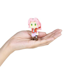 A hand holding a small, pink-haired, pixelated character figure.