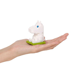 A hand holding a small white toy dinosaur on a green base.