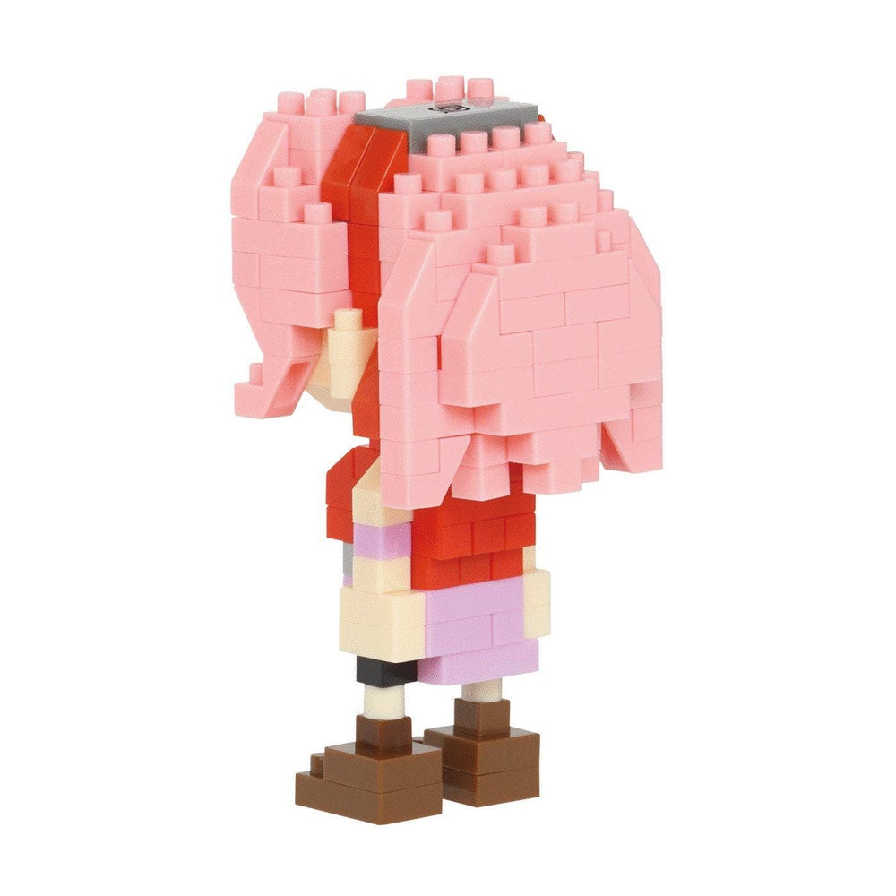 A pink-haired, brick-like figure wearing a red shirt and brown shoes, standing against a white background.