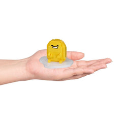 A hand holding a small yellow, pixelated character on a white base.