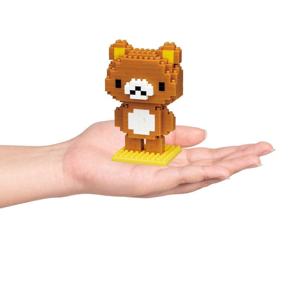 A hand holding a small brown bear-shaped building block figure.
