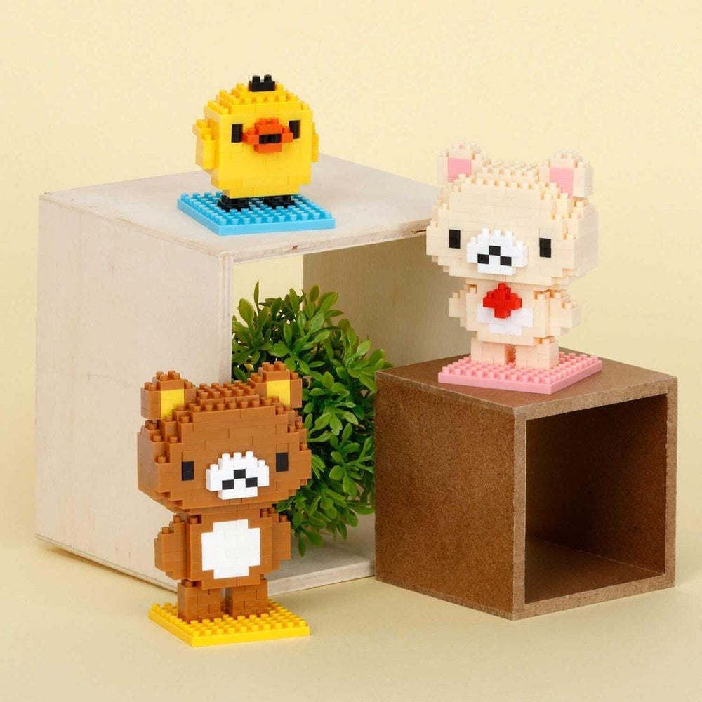 three small, pixelated animal figurines, including a yellow duck, a brown bear, and a pink bear, arranged on a wooden stand.