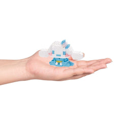 A hand holding a small, white and blue toy, which appears to be a miniature version of a character or object.