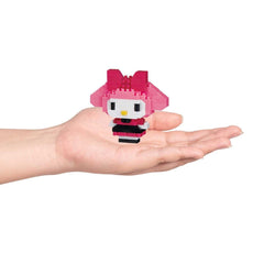A hand holding a small pink and black pixelated character resembling Hello Kitty.