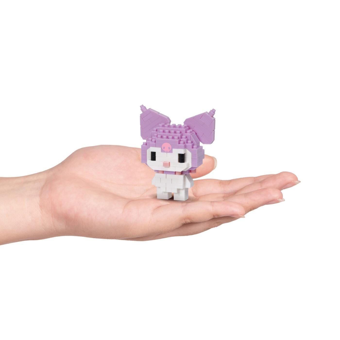 A hand holding a small, purple and white toy resembling a character from a children's television show or movie.