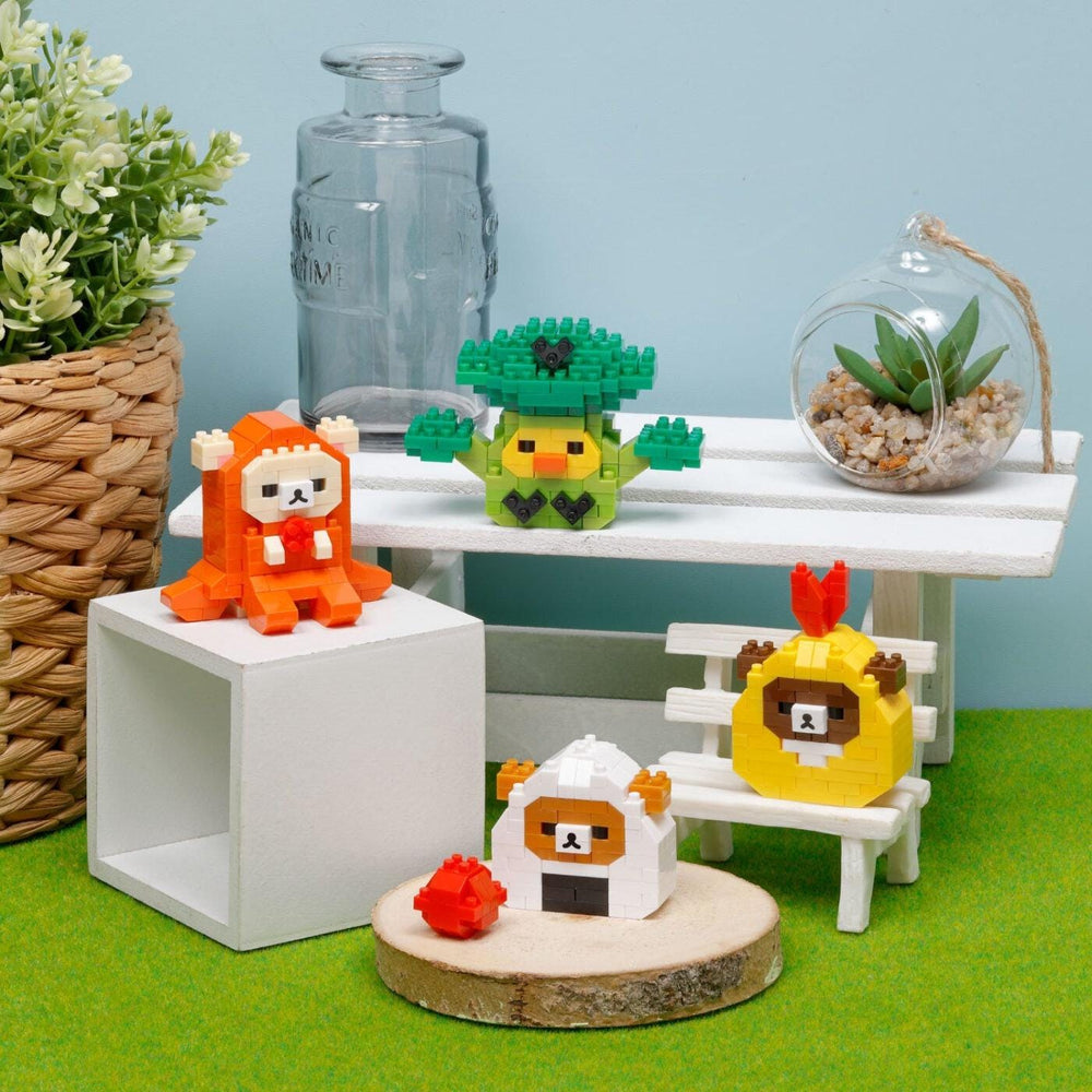 a collection of small, colorful, and whimsical objects, including a small toy animal, a toy bird, and a toy fish, arranged on a wooden surface. There is also a glass vase and a potted plant in the background, adding to the overall aesthetic of the scene.
