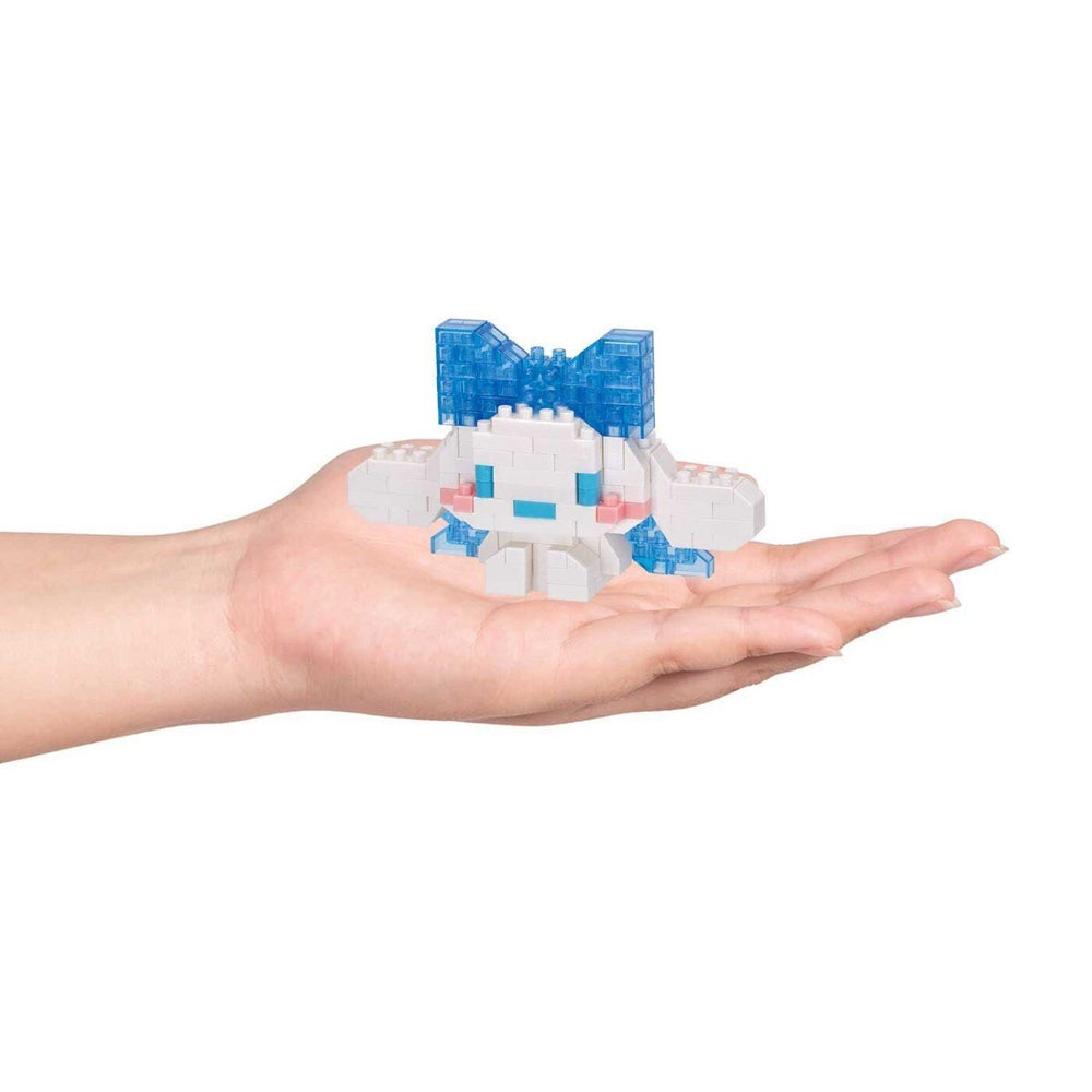 A hand holding a small, white and blue toy, which appears to be a small, colorful building or structure made of small, clear plastic blocks.