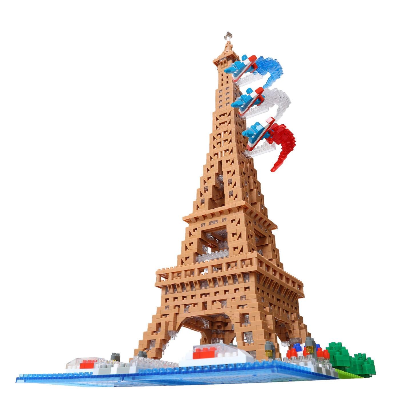 A tall, brown tower made of building blocks, resembling the Eiffel Tower, with a flag attached to the top.