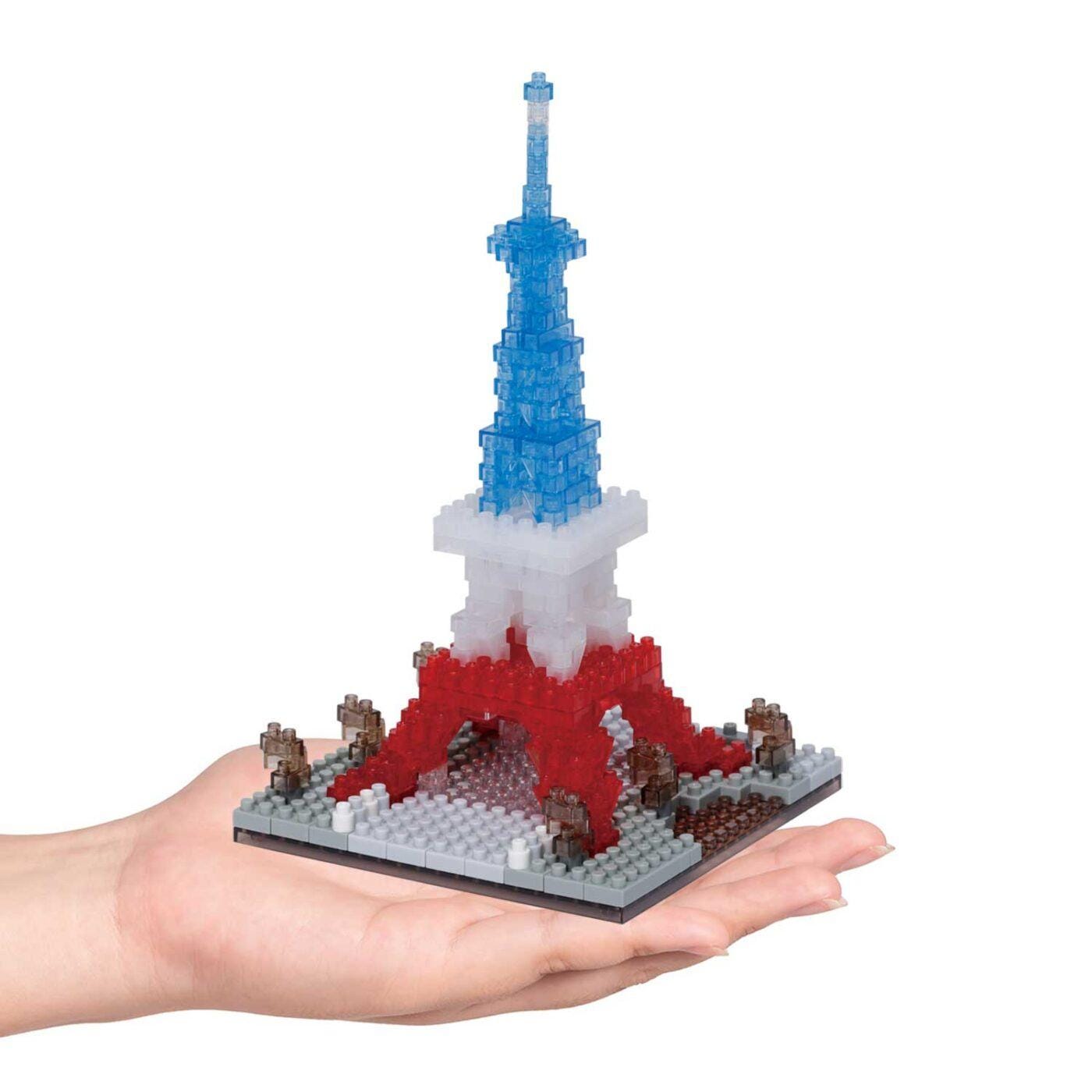 A hand holding a small, colorful, and intricate model of the Eiffel Tower made of small, clear plastic bricks.
