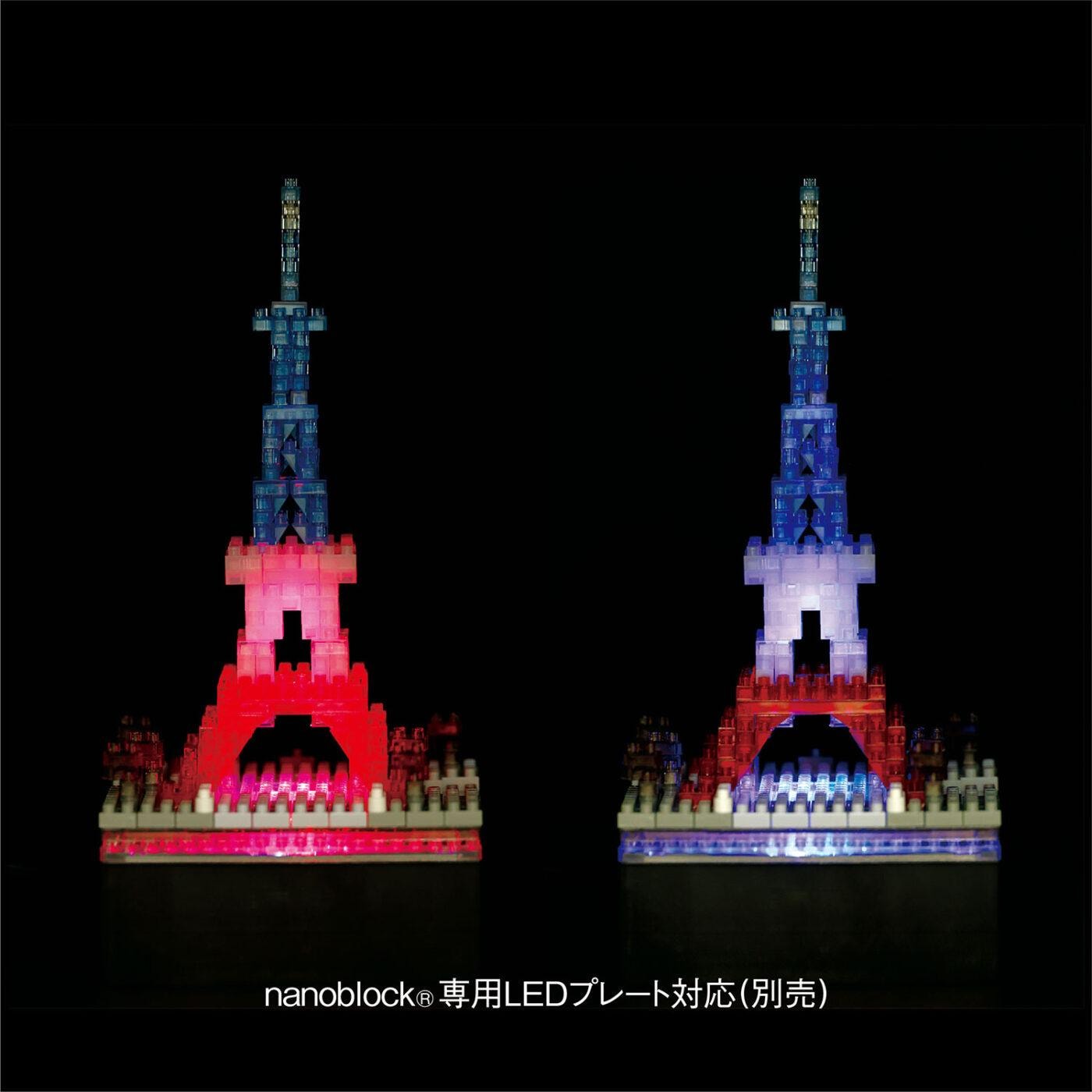 two Eiffel Tower-like structures made of colorful building blocks, illuminated against a dark background.