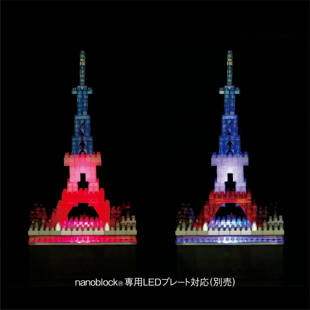 two Eiffel Tower-like structures made of colorful building blocks, illuminated against a dark background.