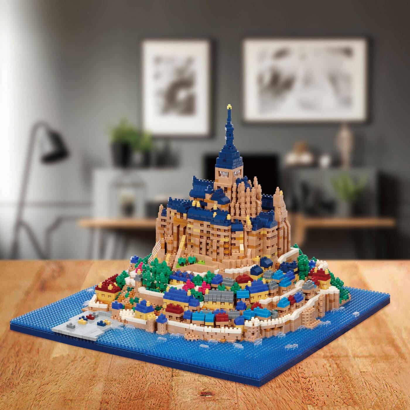 A detailed model of a castle-like structure made of colorful building blocks, resembling a Lego creation, displayed on a wooden surface.