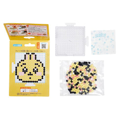 a yellow package with a pixel art design, a clear plastic container with black and pink beads, and a white plastic bag with black and pink beads.