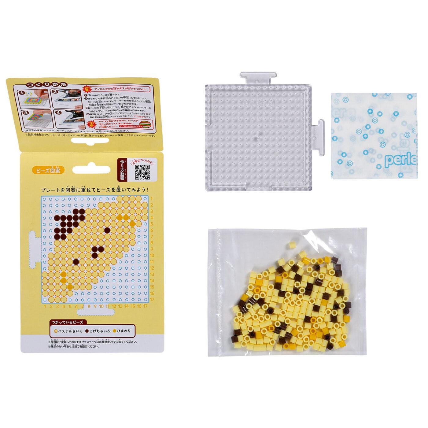 a set of items related to a craft or art project, including a clear plastic container, a yellow box with a pattern, and a bag of yellow and brown beads.