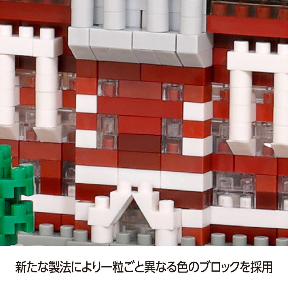 A close-up view of a red brick building made of white and red building blocks, with a green tree visible in the background.