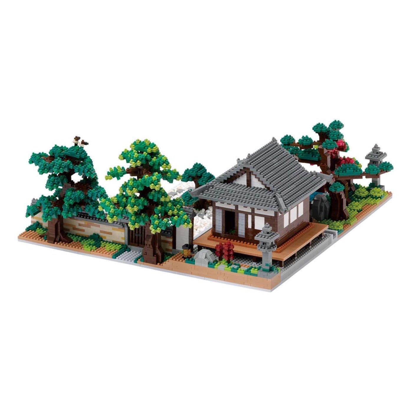 A detailed model of a Japanese-style house with a tiled roof, surrounded by trees and other miniature elements, such as a stone lantern and a small pond.