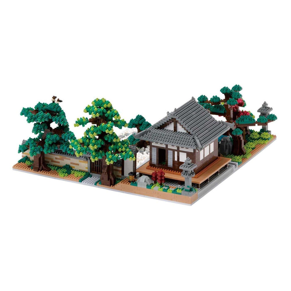 A detailed model of a Japanese-style house with a tiled roof, surrounded by trees and other miniature elements, such as a stone lantern and a small pond.