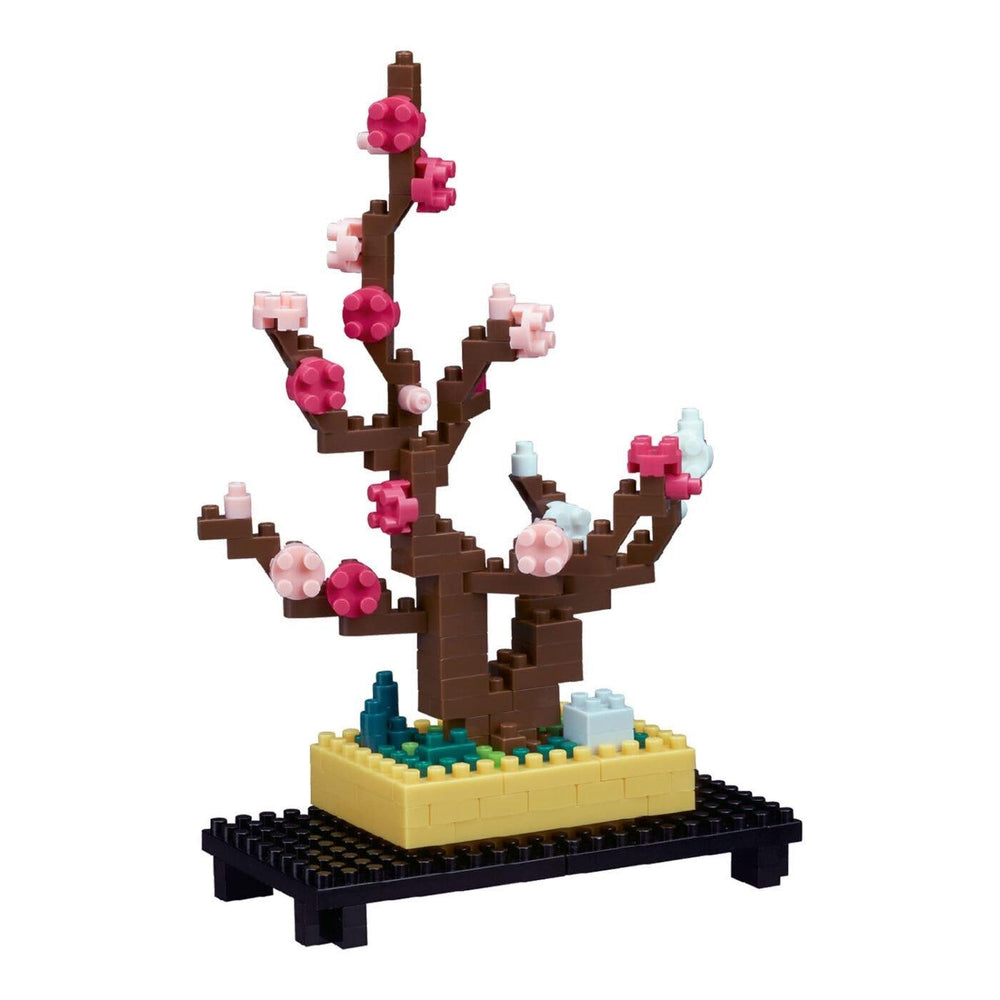 A colorful, pixelated tree made of building blocks, with pink flowers and a yellow base, sitting on a black stand.