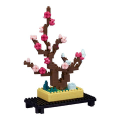 A colorful, pixelated tree made of building blocks, with pink flowers and a yellow base, sitting on a black stand.
