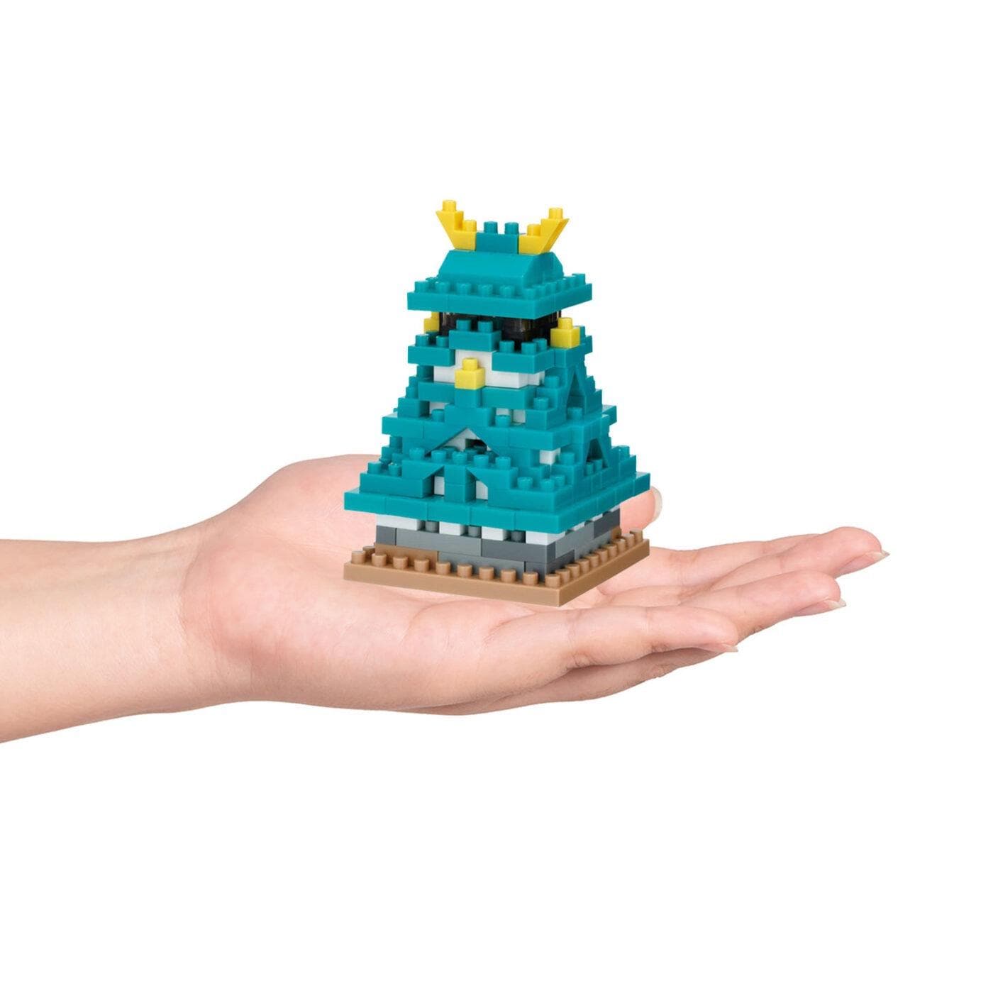 A hand holding a small, colorful, and intricate model of a building or structure made of small, blue and yellow building blocks.