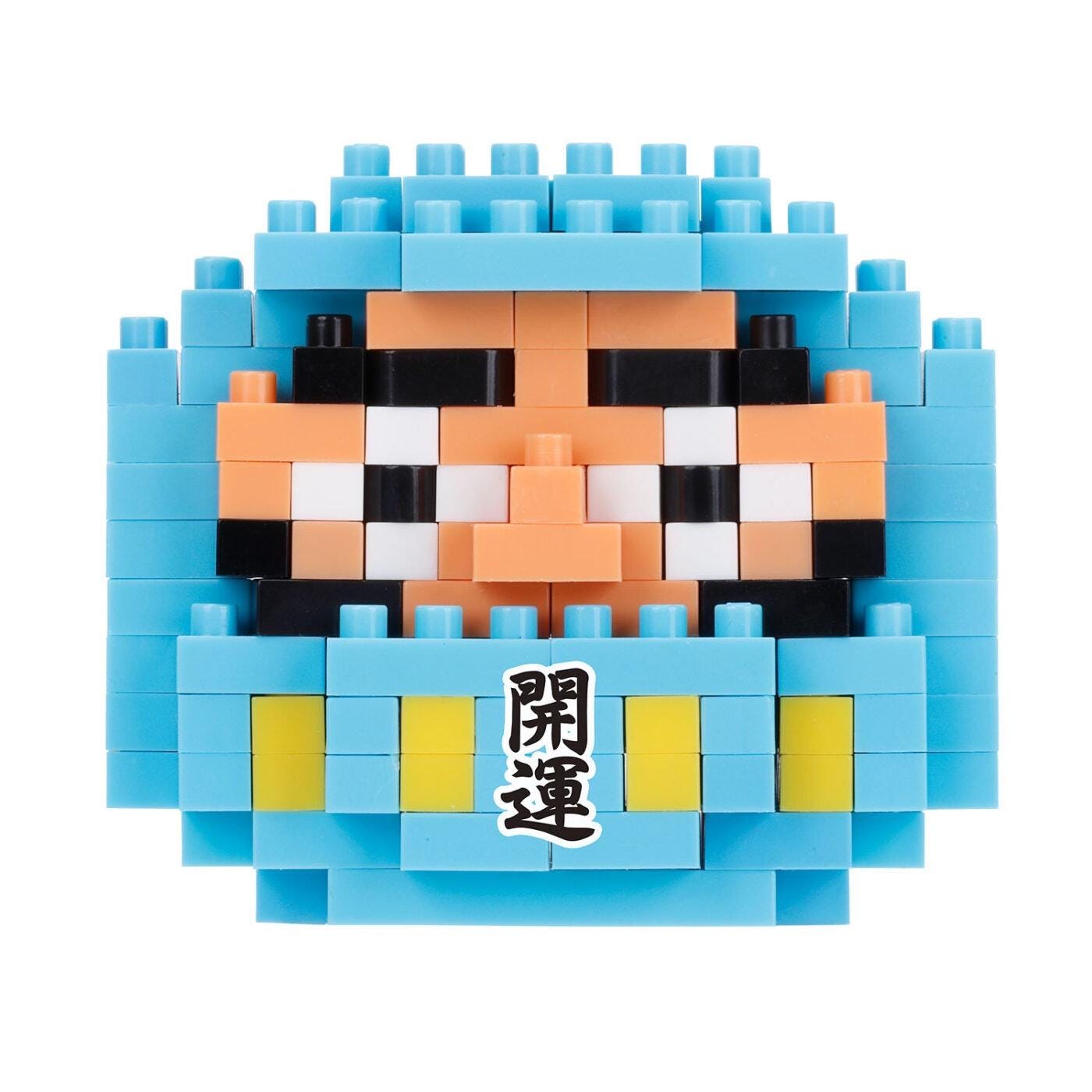 A pixelated image of a character composed of blue and orange blocks, with a small label in the center that contains Japanese text.