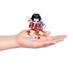 A hand holding a small, colorful, and intricate toy figure made of building blocks.