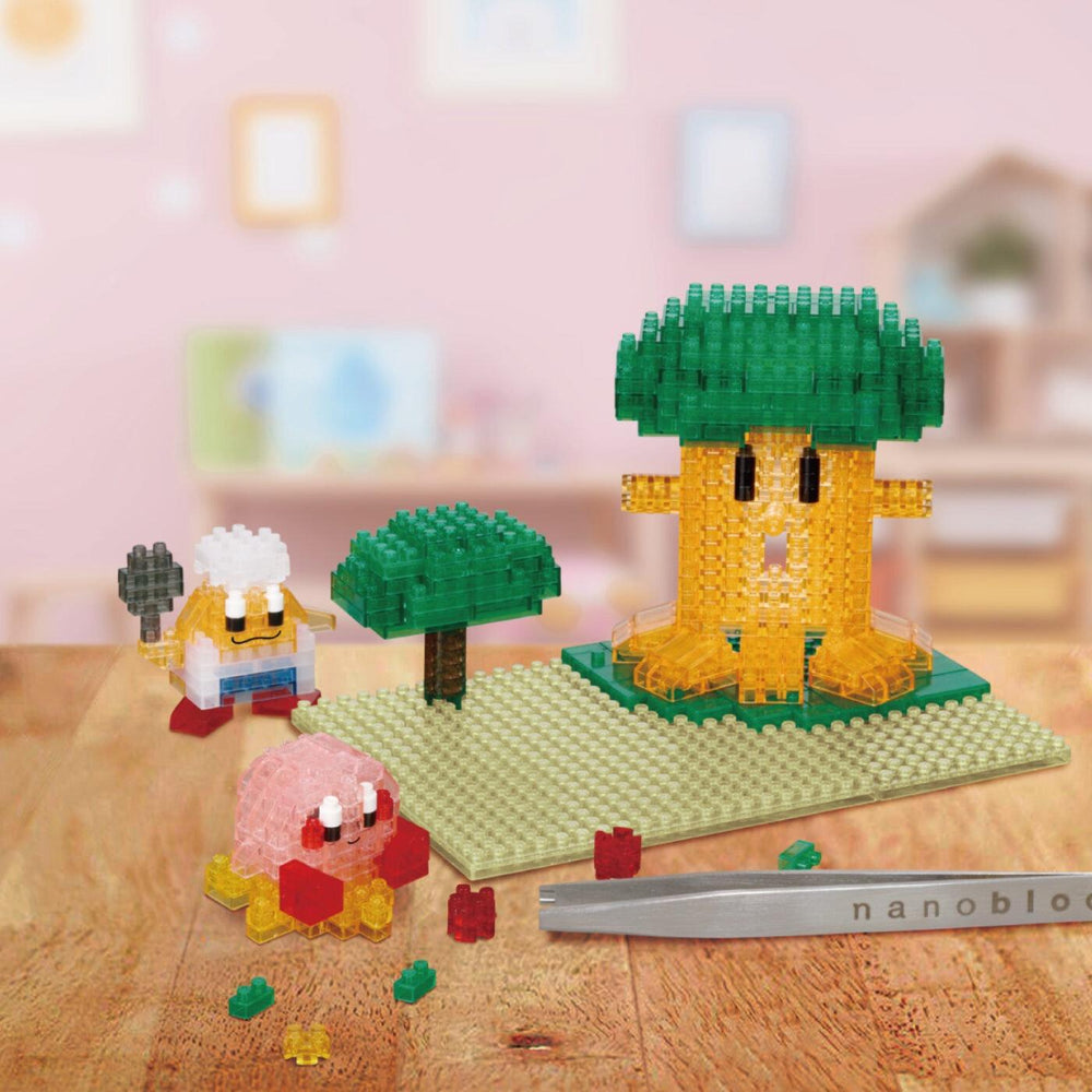 A collection of colorful, pixelated characters and objects, including a green tree-like structure, a pink character, and a yellow character, arranged on a wooden surface.
